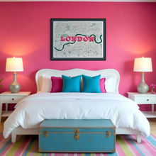 Load image into Gallery viewer, A framed, screen-printed London map hangs on a bright pink bedroom wall above a white bed with white linens, turquoise and magenta pillows, a blue trunk at the foot, and matching bedside tables and lamps.