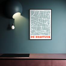 Load image into Gallery viewer, A framed vintage-style screen-printed map art print of De Beauvoir Town, London, hanging on a dark teal wall in a modern kitchen setting with a black pendant light and wooden countertop.