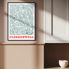 Load image into Gallery viewer, A framed street map art print of Clerkenwell with bold orange text at the bottom, displayed on a beige wall in a modern interior setting with soft window shadows.

