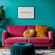 Load image into Gallery viewer, A framed street map print of 'Islington' with coral pink lettering hanging on a vibrant teal wall above a bright pink sofa with yellow and gold pillows.
