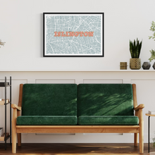 Load image into Gallery viewer, A framed screen-printed map of Islington with the word 'ISLINGTON' in coral text, hanging on a white wall above a green velvet two-seat sofa in a modern living room setting.
